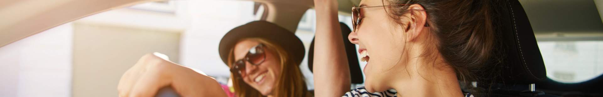 VRK Fahrerschutz – Junge Frau sitzt mit ihrer Freundin in Ihrem Auto.